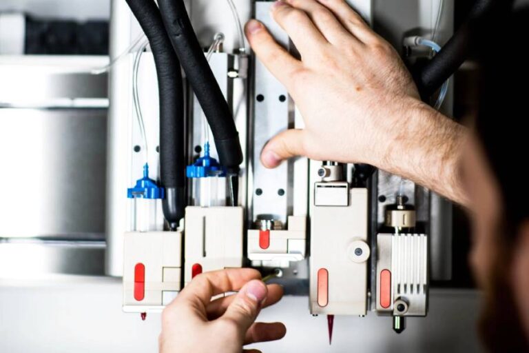 Detalle de bioimpresora 3D RegenHU R-Gen 100 con manos de hombre